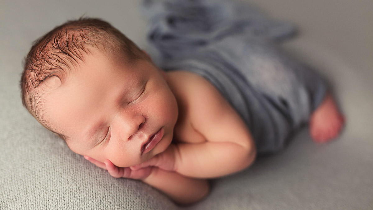 newborn studio portrait of a baby boy in a blue wrap in ankeny iowa at my home photographer studio