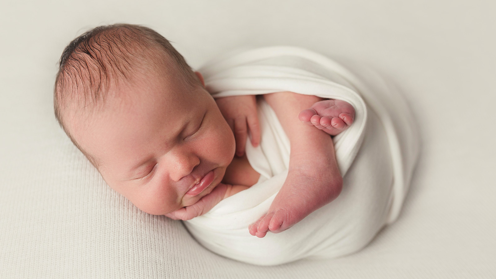 newborn studio portrait of a baby girl in a white wrap in ankeny iowa at my home photographer studio