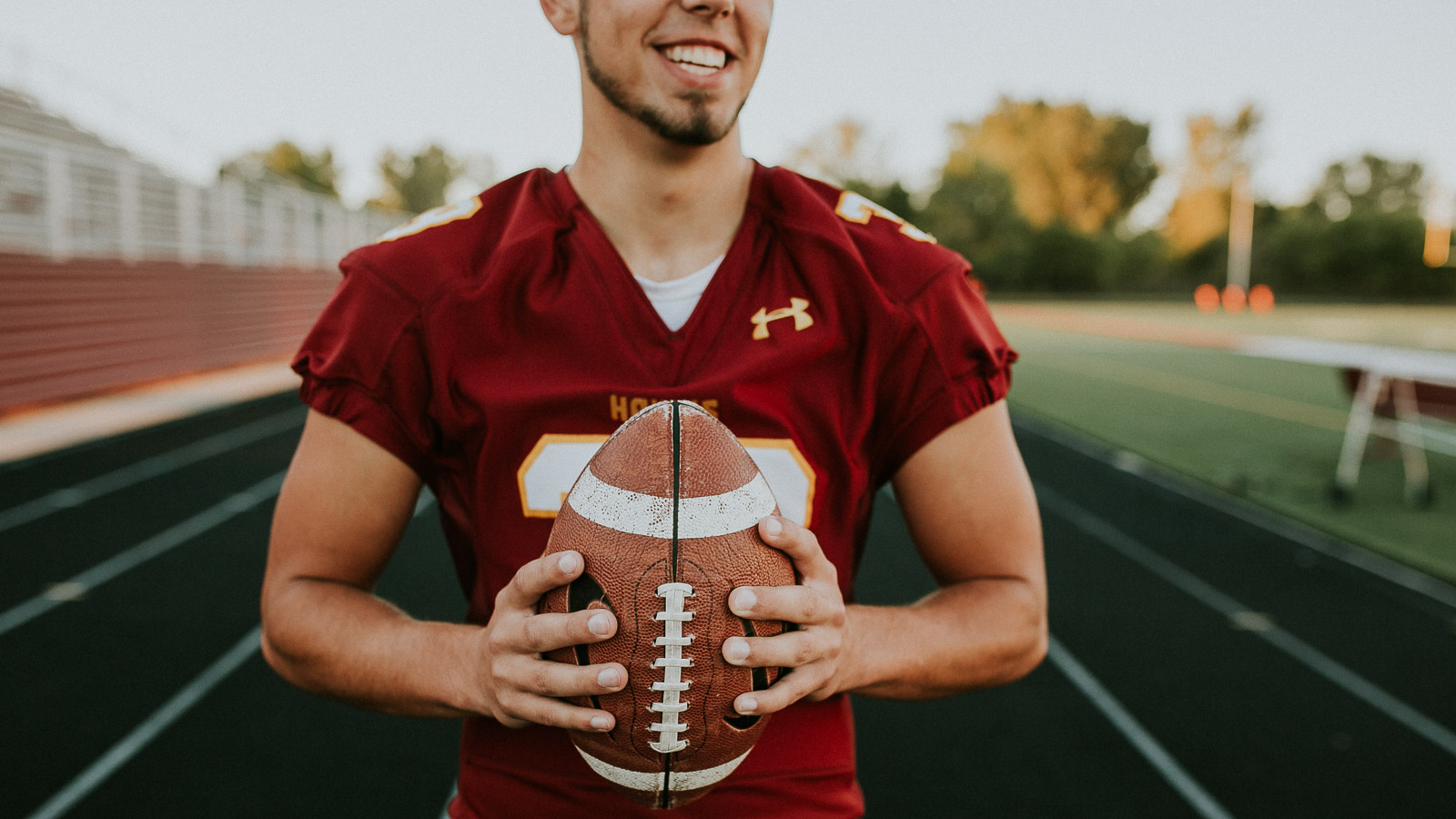photograph of a senior boy at the ankeny south hawks football field in ankeny iowa